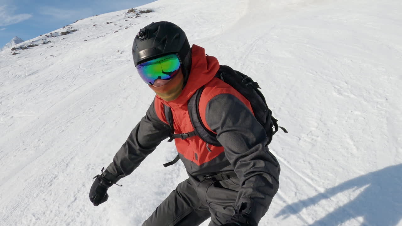Young male skiing down snow covered hill on snowboard, Caucasus mountains, selfie portrait