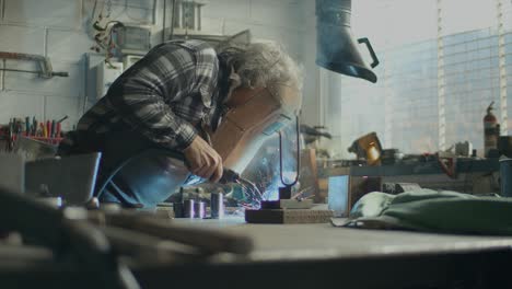 slider shot of blacksmith welding in workshop, sparks flying in air