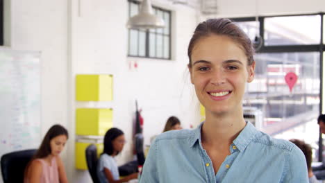 young white woman in office walks into focus and smiles