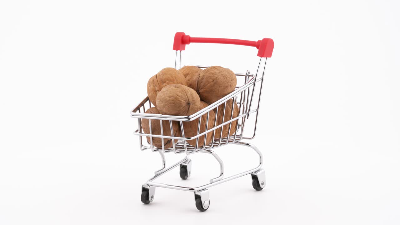 un carrito de compras lleno de nueces girando en la mesa giratoria. aislado en el fondo blanco. primer plano.