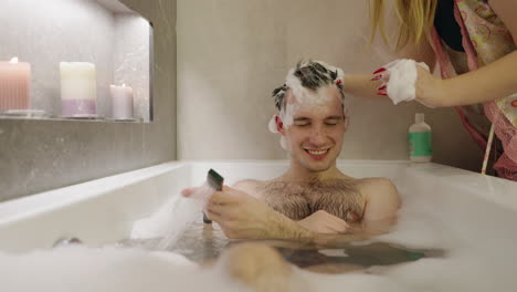 hombre tomando champú en la bañera mientras usa el teléfono