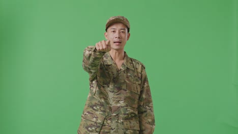 asian man soldier shouting to camera while standing in the green screen background studio