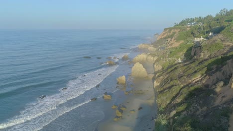 aerial shots of el matador beach over breaking waves and rocks on a hazy summer morning in malibu, california