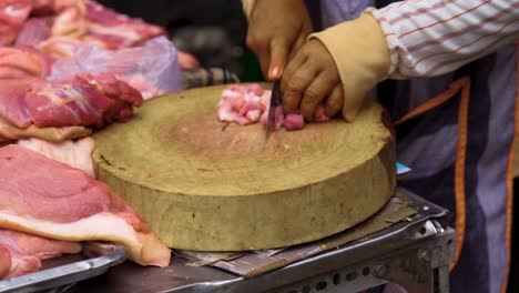 butcher chopping up meat on a wood block in a wet market in southeast asia