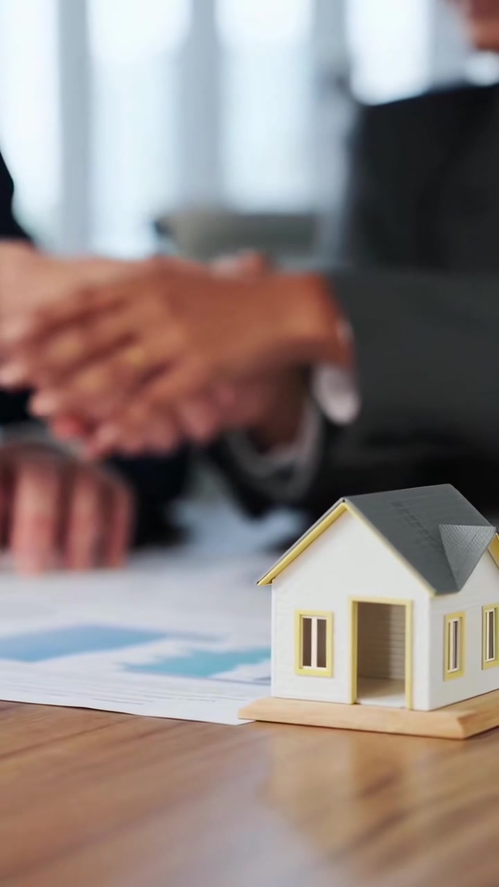 Profesionales de negocios cerrando un trato inmobiliario con una maqueta de casa
