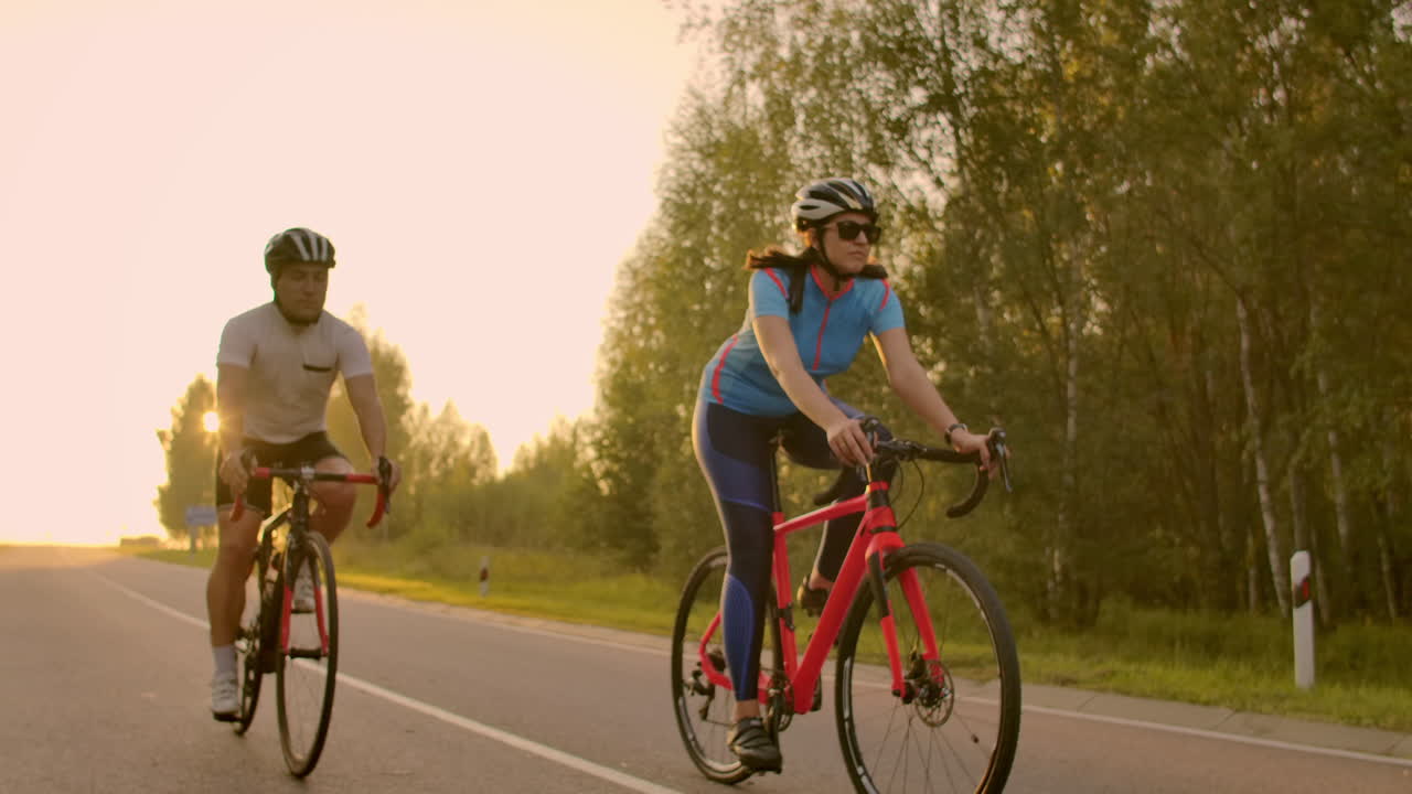 espacio vacío. amigos deportivos en bicicleta al atardecer. pareja de ciclistas van a lo largo de la costa. deporte en el fondo de la naturaleza. grupo de personas dos ciclistas de carretera al atarrear el sol.