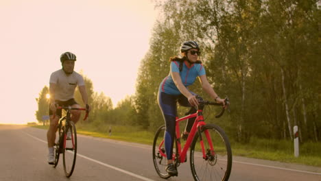 Espacio-Vacio.-Amigos-Deportivos-En-Bicicleta-Al-Atardecer.-Un-Par-De-Ciclistas-Van-Por-La-Costa.-Deporte-En-El-Fondo-De-La-Naturaleza.-Grupo-De-Personas-Dos-Ciclistas-De-Carretera-Al-Atardecer.