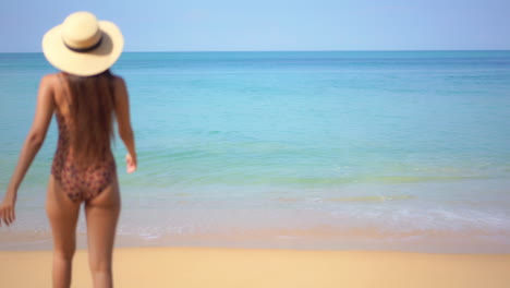 Vista-Trasera-De-Una-Joven-Caminando-Por-La-Playa-Levantando-Los-Brazos-Y-Mirando-El-Horizonte