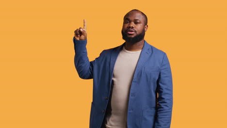 man looking up, showing something to audience, studio background