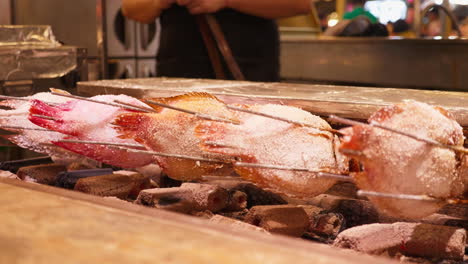 grilled fish on a stick at a street food market