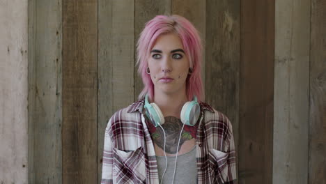 young punk girl portrait of attractive woman with pink hairstyle looking awkward at camera wooden background