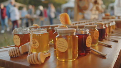 variety of honey jars and dippers on display at an outdoor market