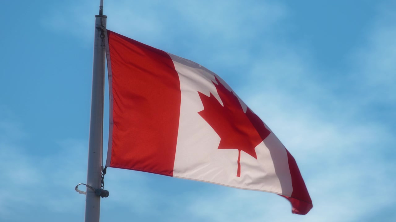 Bandiera canadese che sventola al vento contro il cielo blu. Rallentatore.