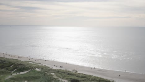 panoramic shot from the top of blåvand lighthouse, denmark starting in the dunes with houses and panning over to reveal the ocean, capturing the expansive coastal view of denmark with overcast sky