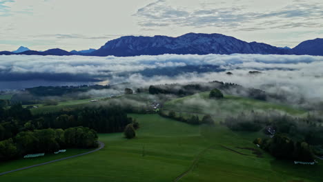 aerial view of a misty landscape with lush greenery and a mountain range in the background