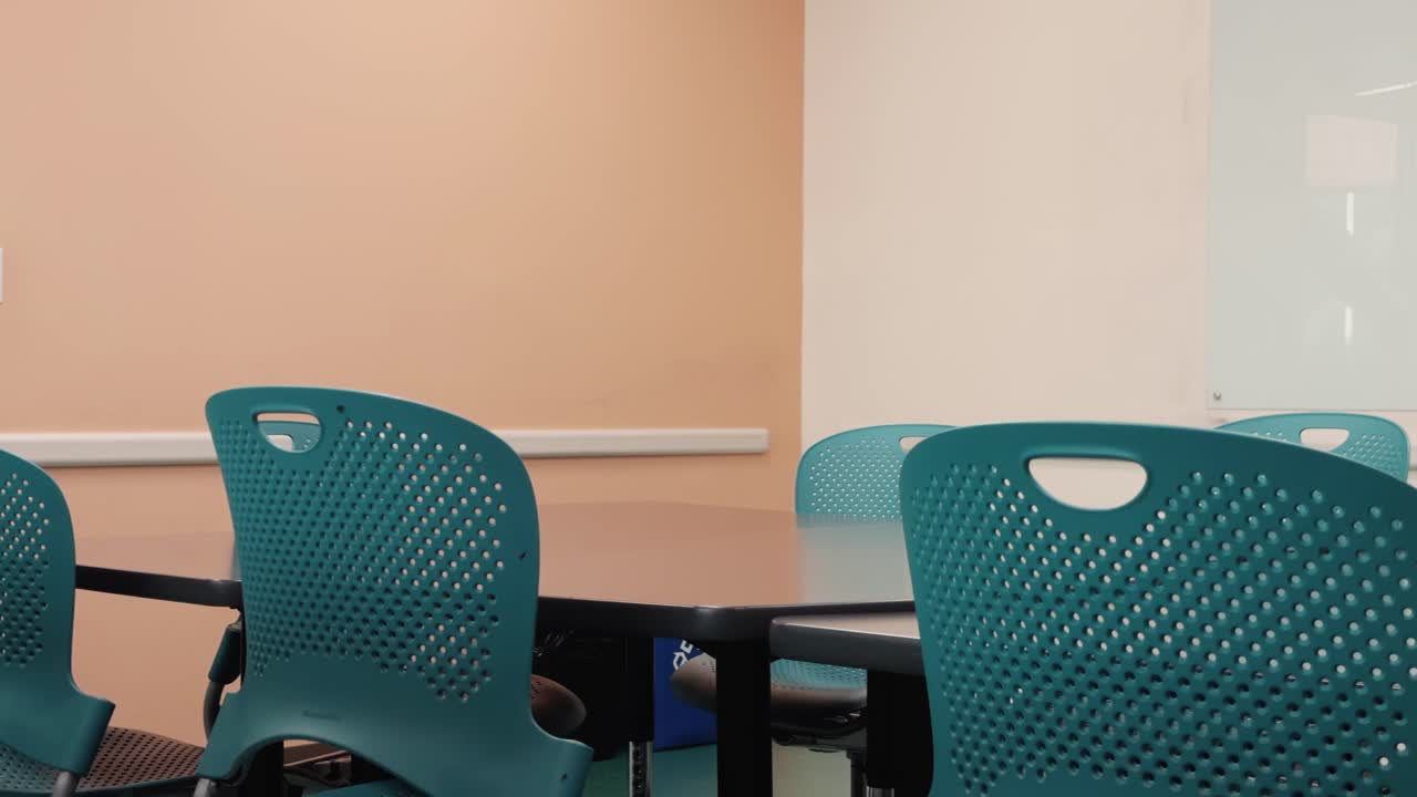 Slow steady pan across empty conference room with table, chairs, and whiteboard