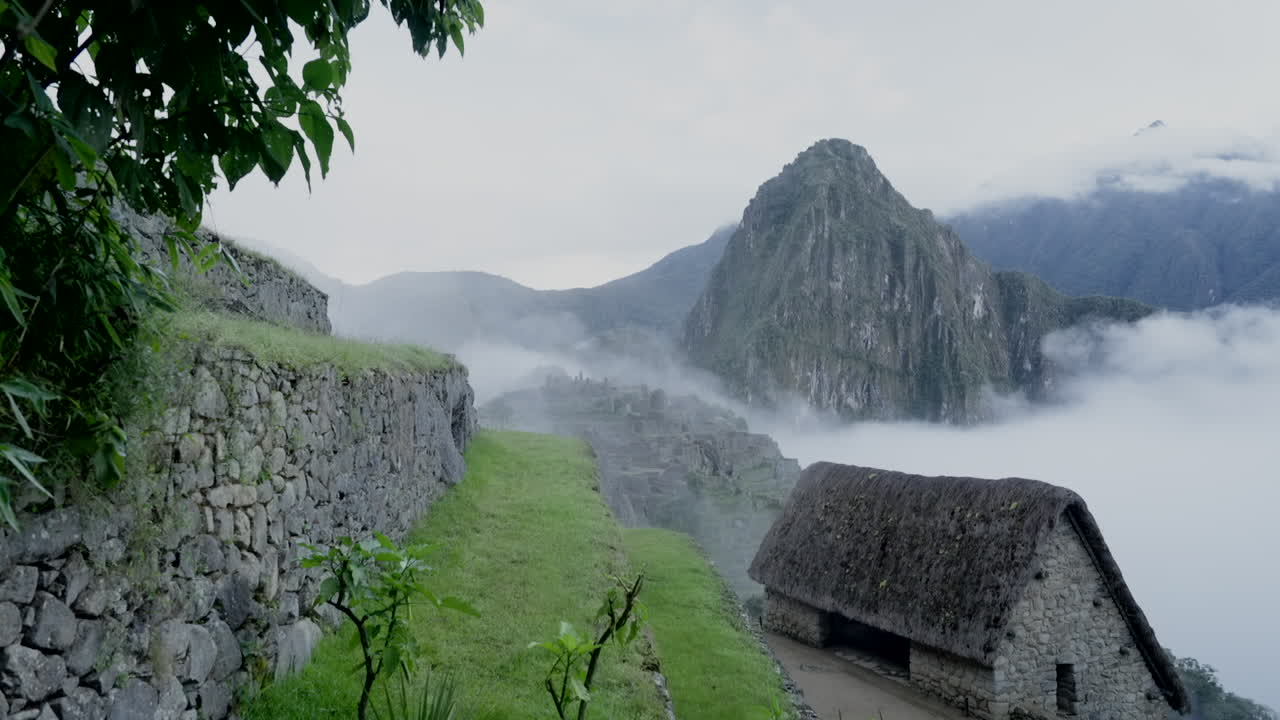 Zoom out of Machu Picchu and Huayna Picchu in cold rainy morning. Lost city Inca citadel. Establishing