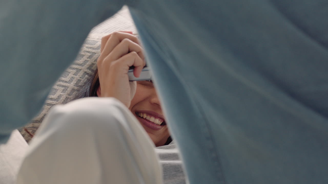 행복한 커플이 카메라를 사용하여 함께 사진을 찍고 재미있게 소파에서 집에서 휴식을 취하고  ⁇ 만적인 관계를 즐기며 서로 사진을 찍고 있습니다.