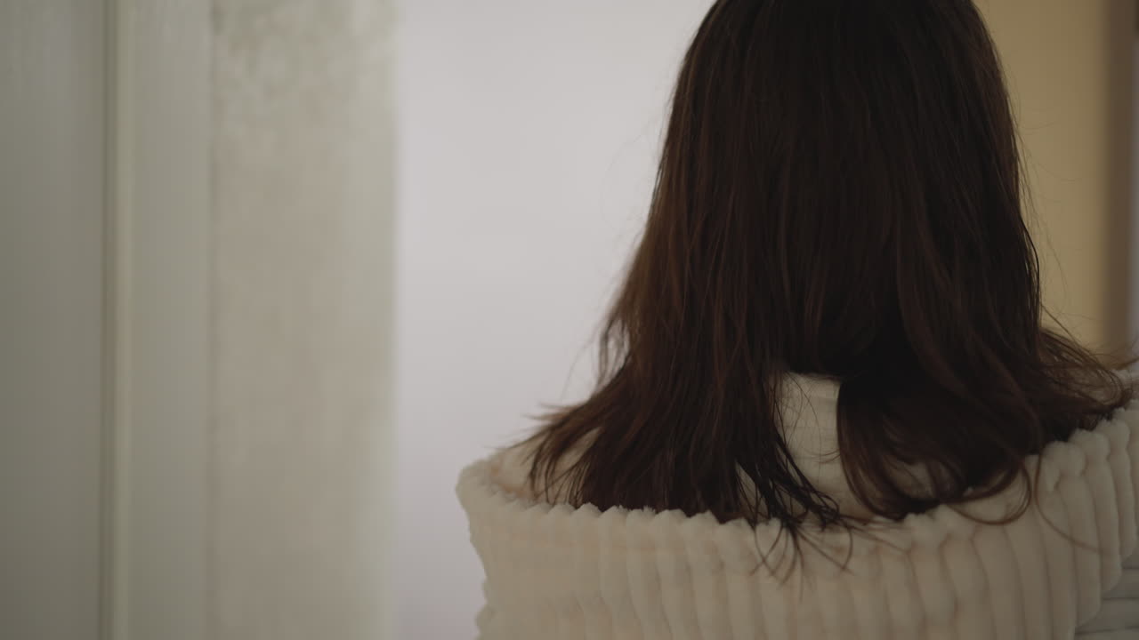 아파트를 가로질러 걸어가는 여성은 스폰지로 얼굴을 고 있습니다. 갈색 여성은 샤워에서 나오고 화장품 스폰지를 가진 거울에 접근합니다.