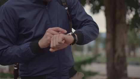 hombre comprobando el reloj inteligente al aire libre