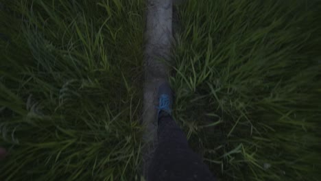 Feet-walking-through-tall-grass-and-concrete-slabs