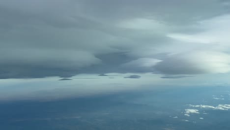 paisaje nublado volando a través de un cielo lleno de nubes lenticulares de invierno, disparado desde una cabina de avión, como lo ve el piloto