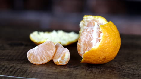 close up of half peeled orange on dark wooden surface