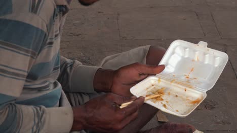 close shot of a cambodian man finishing eating from a polystyrene container