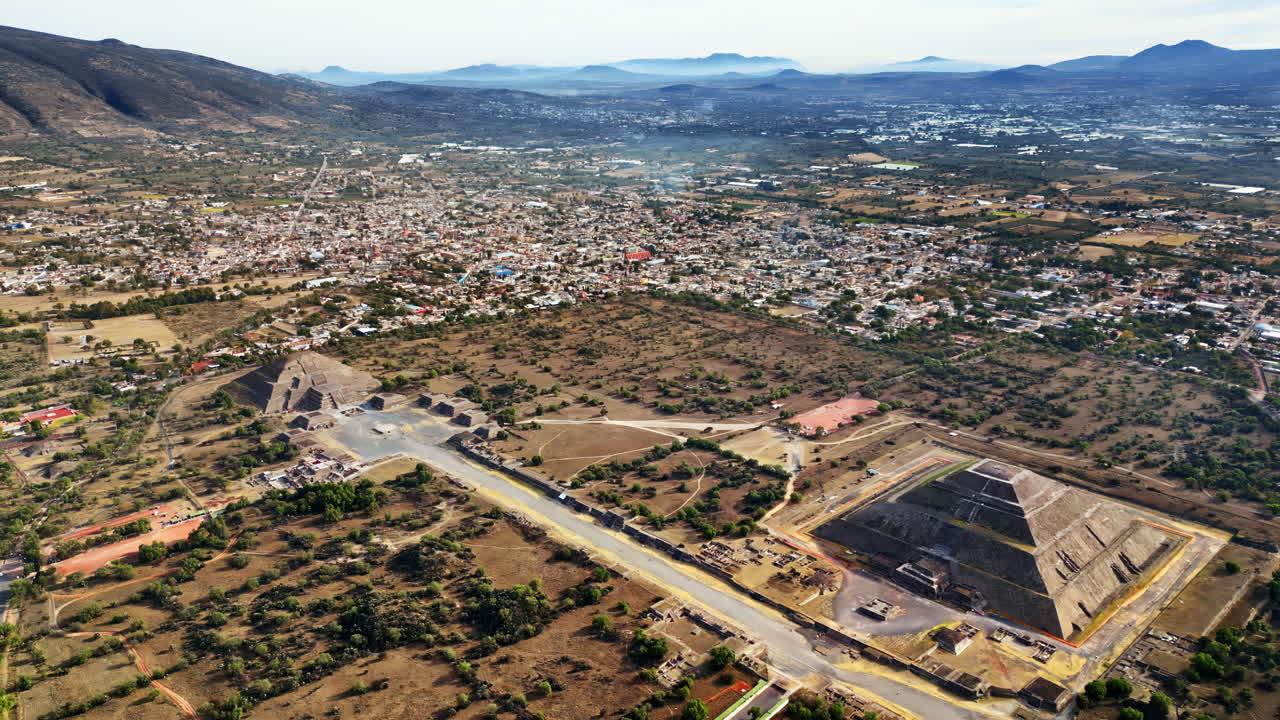 Aerial drone view of the ancient Teotihuacan pyramids with the surrounding Mexican town and mountain landscape
