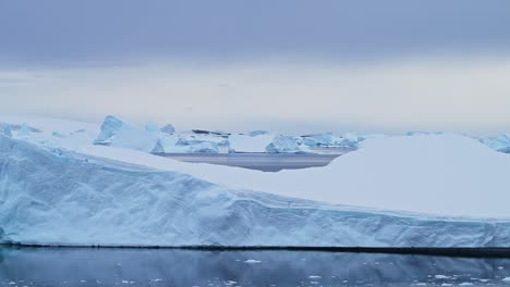 Big-Antarctica-Iceberg-Landscape-Sunset,-Large-Massive-Blue-Icebergs-with-Amazing-Shapes-and-Dramatic-Couds-and-Sky-in-Sunrise-Winter-Seascape-Scenery-on-Antarctic-Peninsula-in-Icy-Scene