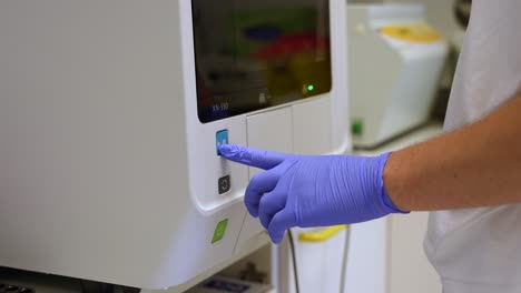 a laboratory technician loading a blood sample into an analyser for medical analysis