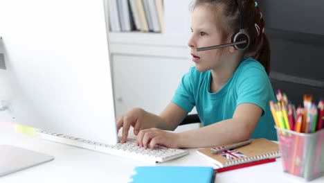young girl engaged in online learning with headset and computer