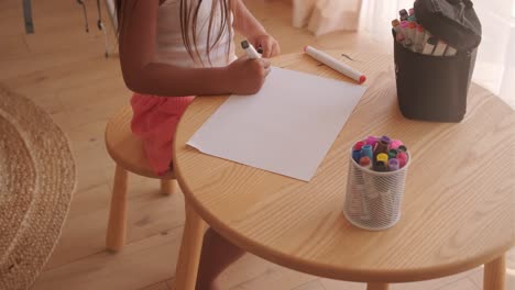 child drawing with markers at table