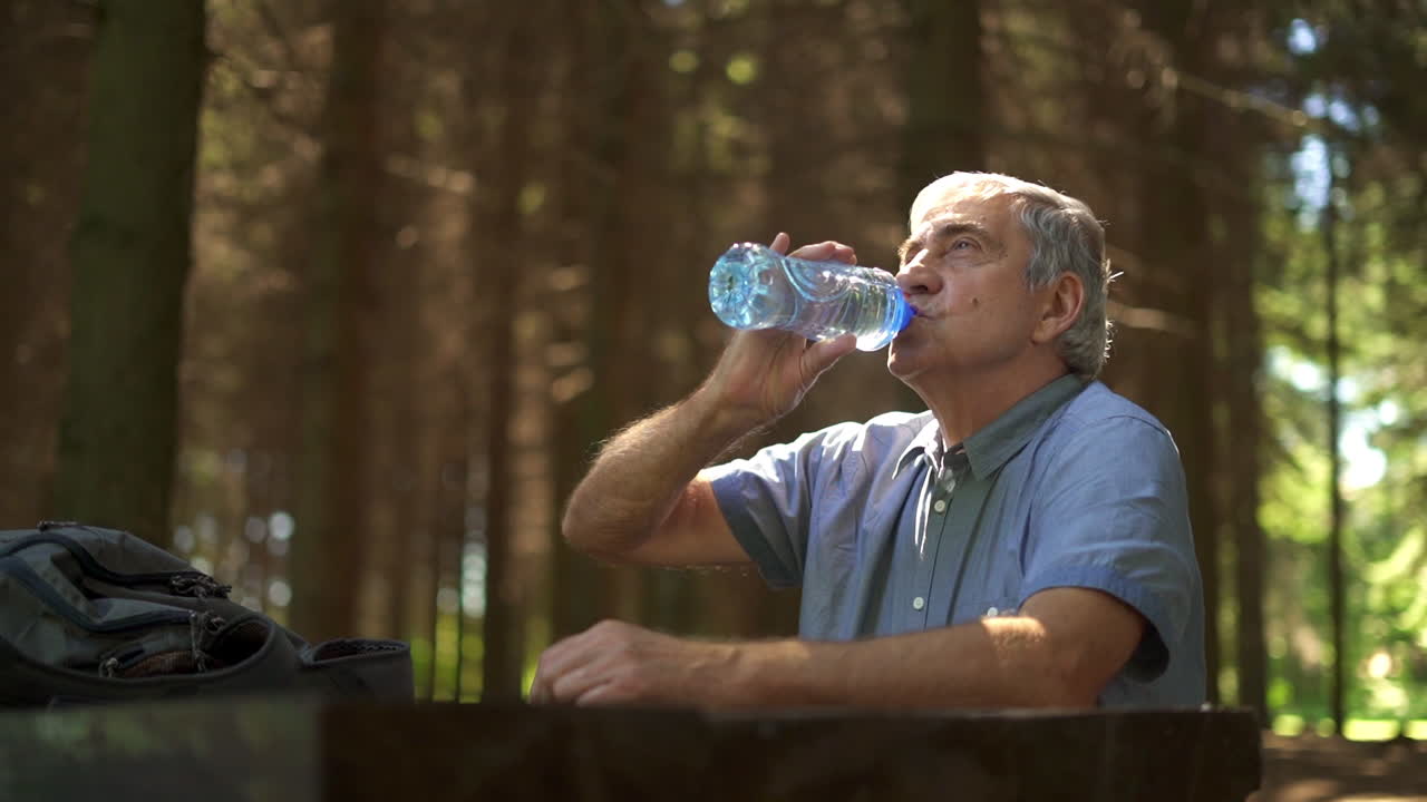 Senior man drinking water in forest