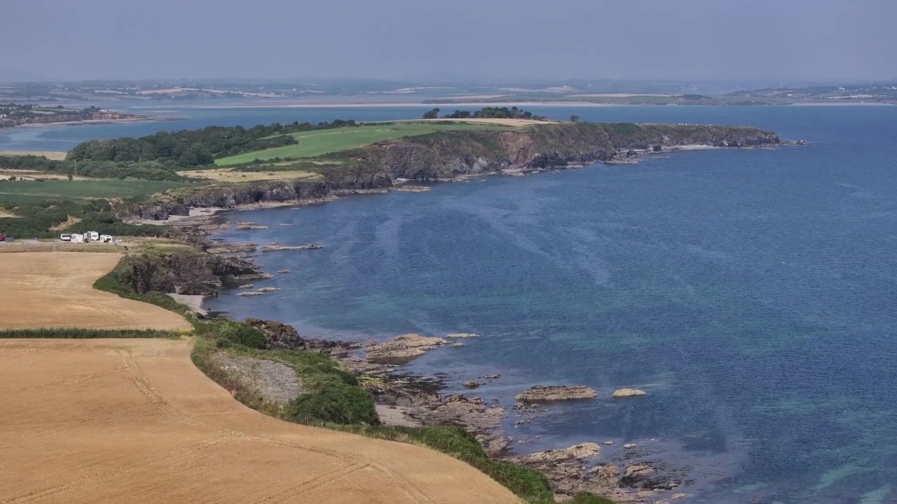 Vue aérienne en plongée de la côte irlandaise accidentée à Ramstown Bay, avec des eaux bleues, des falaises rocheuses et des champs agricoles dorés