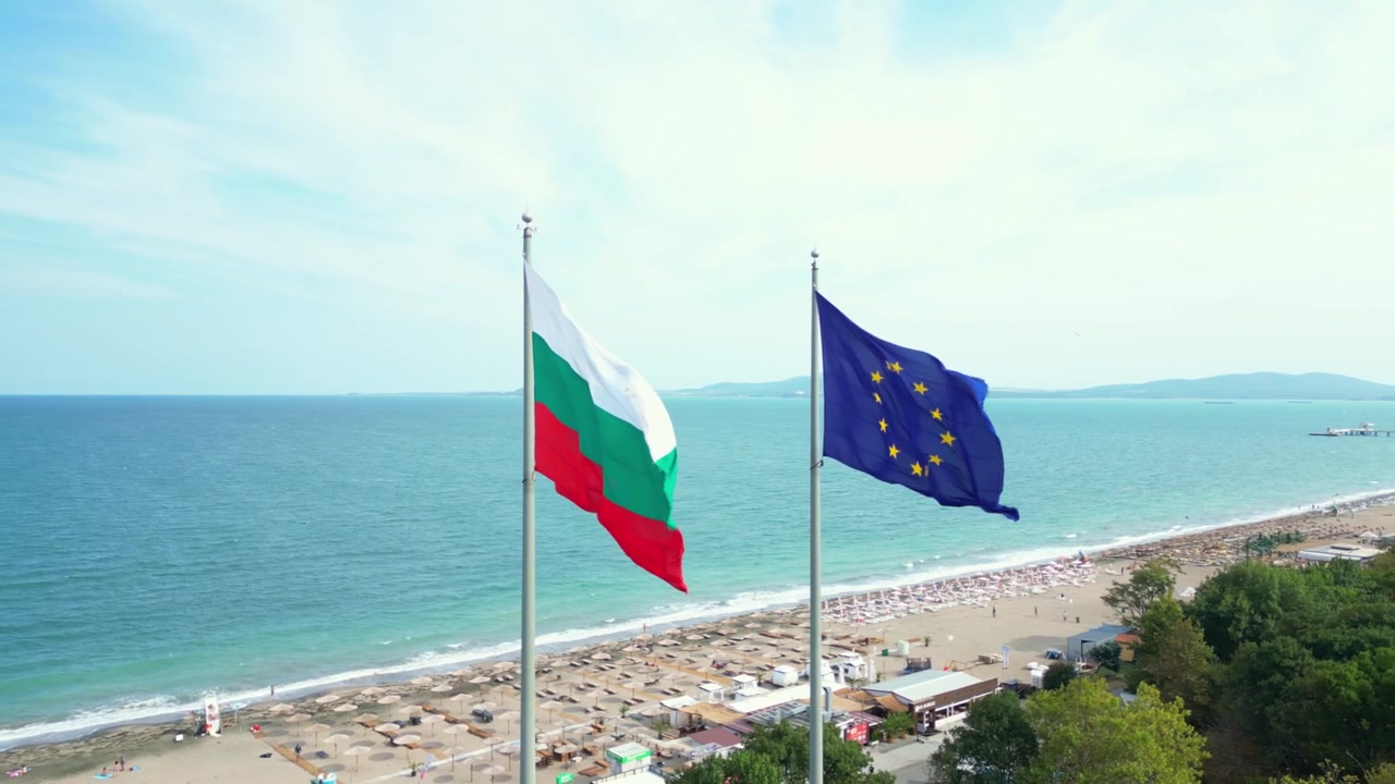 Al rallentatore, il drone rivela le bandiere bulgara e dell'Unione Europea sopra la costa di Burgas, Bulgaria, con la spiaggia e il Mar Nero sullo sfondo.