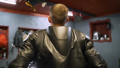 man in motorcycle leather jacket in a garage