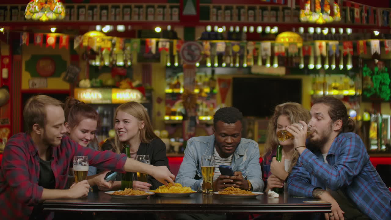 다양한 친구 그룹이 토스트와 함께 축하하고 다양한 음료와 함께 상승 한 컵을 걱거립니다. 아름다운 젊은이들은 세련된 바 및 레스토랑에서 재미있게 즐기고 있습니다.