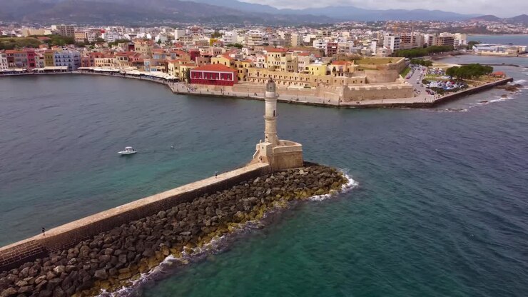 Ripresa cinematografica circolare del faro di Chania sullo sfondo del centro storico di Chania e delle onde agitate del mare - Creta, Chania