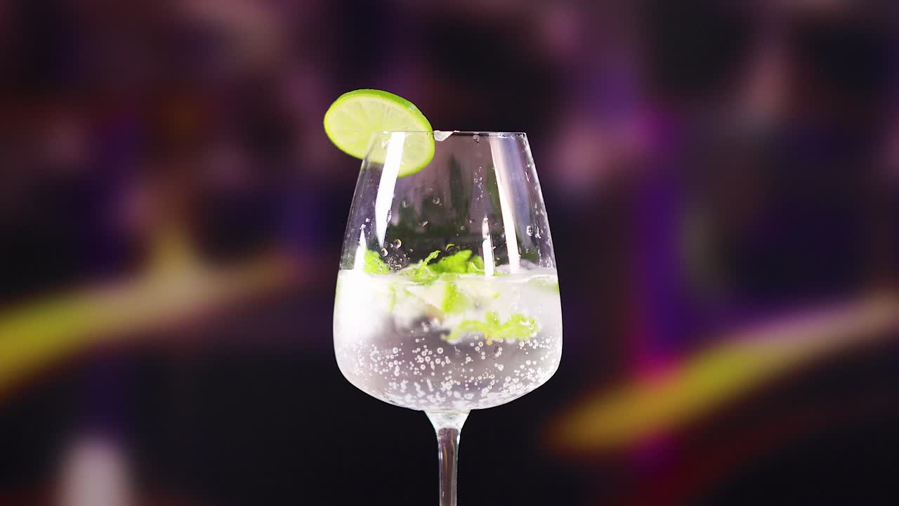 A mojito cocktail with lime and mint in a lively bar environment, featuring dynamic lighting and vibrant colors