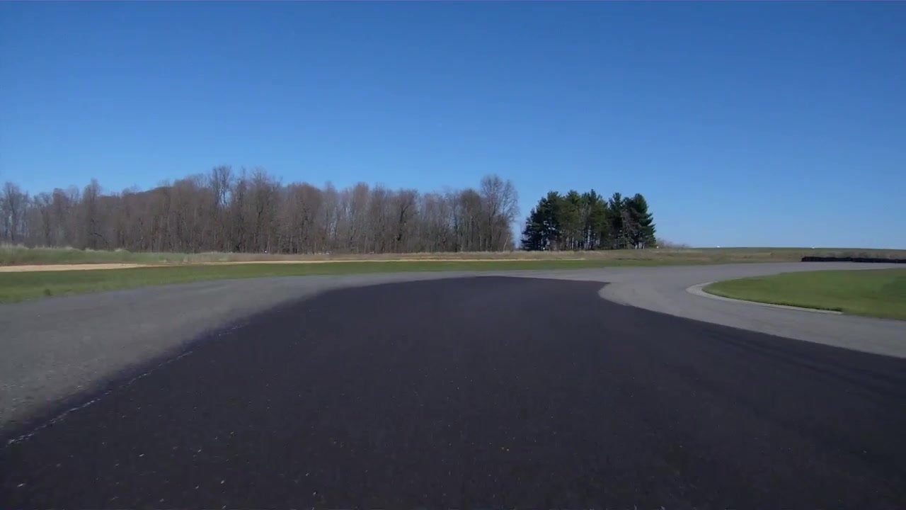 Racing sports car speeding around the circuit on a sunny day.
