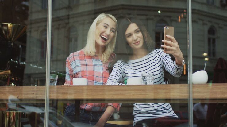 Amiche affascinanti che si scattano selfie in un caffè