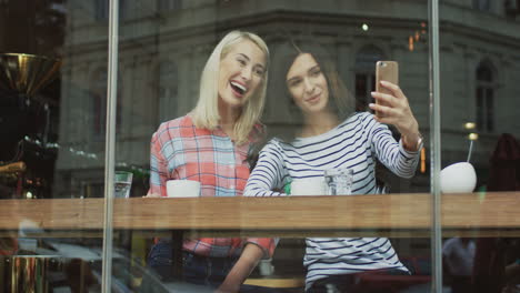 charming female friends taking selfie photos in a cafe