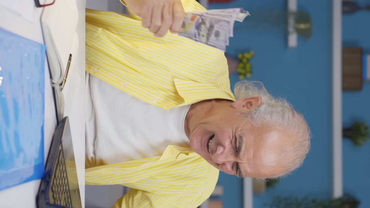 홈 오피스 직원 노인이 돈을 벌고 행복하다고 느끼는 수직 비디오입니다.