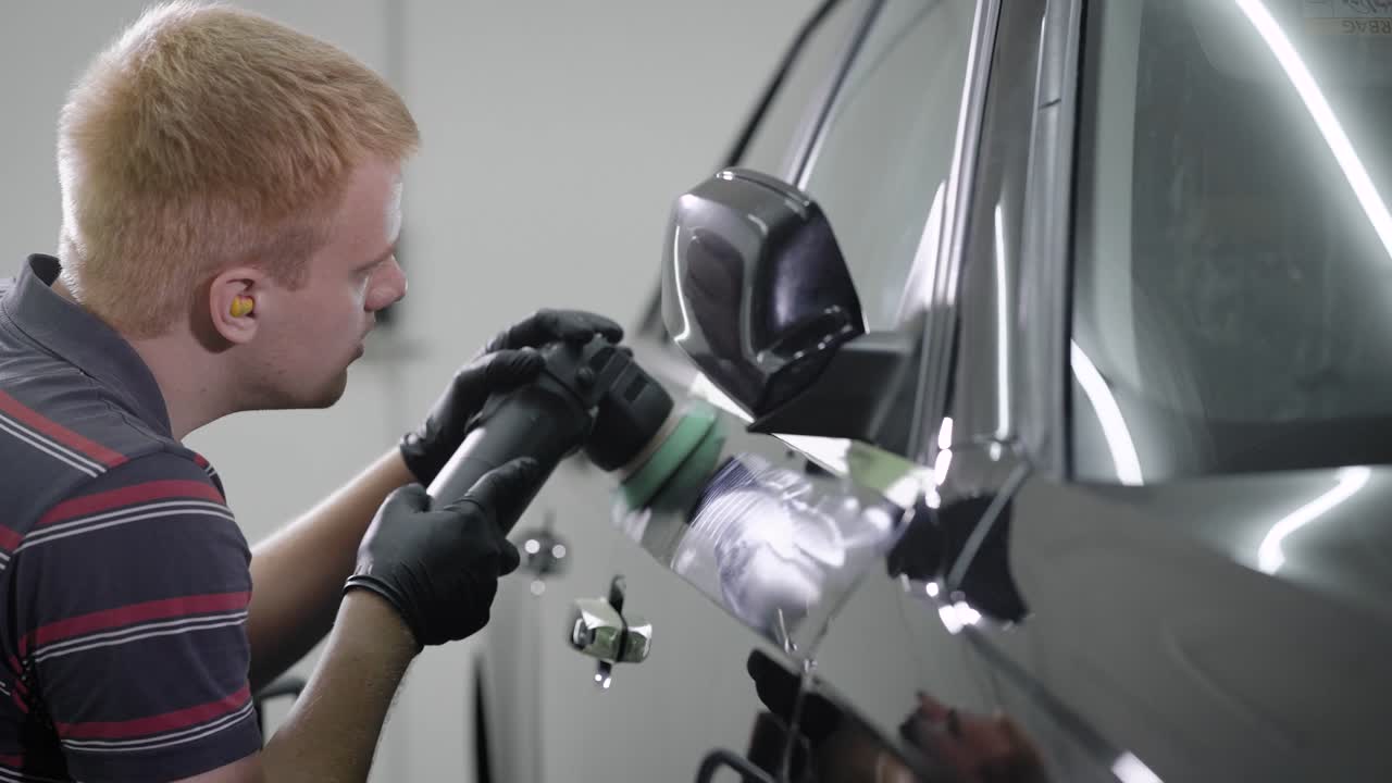 노동자는 자동차 염료에 보호 커버를 만들고, 오토 서비스에서 회전 는 기계로 마사지합니다.