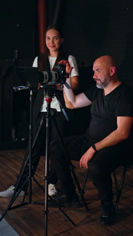 positive man and woman working backstage in studio. people taking video using professional equipment. vertical video