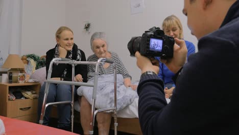 Family-visiting-elderly-grandmother-and-taking-photo-with-her