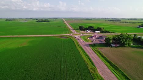 aerial view of a lowboy trailer semi truck entering a rural truck stop near agricultural fields.