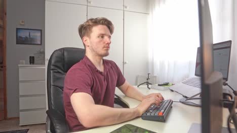 a young man sits down at the desk of his home office