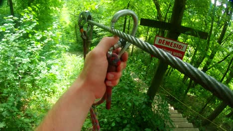 a man fastens a carbine on a metal rope in the forest